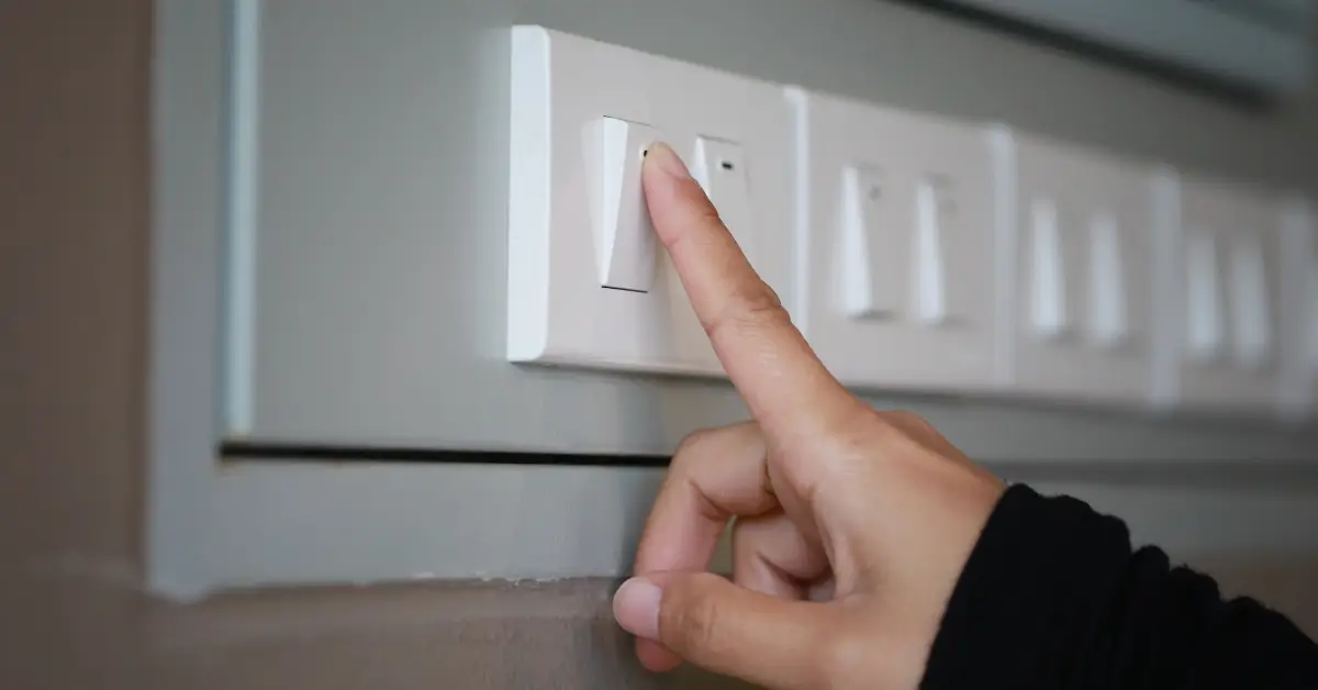 Homeowner testing a light switch panel by turning switches on and off during a home electrical inspection.